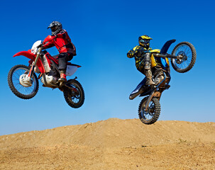 Extreme to the max. Action shot of two dirt bikers jumping in different directions.
