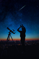 Silhouette of a man while watching starry skies with astronomy telescope and binoculars.