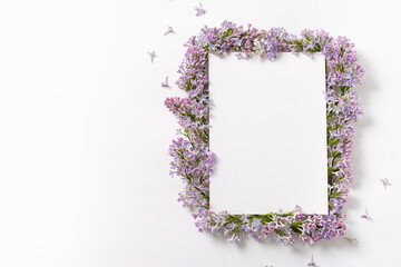 Purple lilac flower frame and empty sheet of paper template on white background with copy space for text. Top view minimal composition. Floral invitation, greeting card, poster. Spring sale background