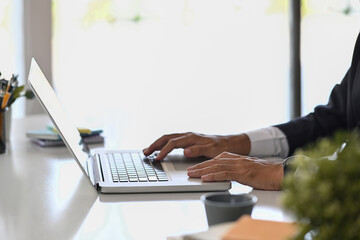 Cropped shot businessman hand typing on laptop computer while working at office desk.