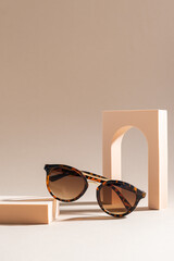 Trendy Tortoiseshell frame sunglasses on beige background. Trendy sunglasses still life in minimal...