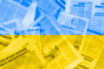  Abstract image of newspapers on the background of the flag of Ukraine. News media concept. Blur,...