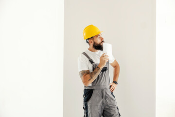 A blue collar worker standing in painted room and planning next step.