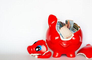 Red piggy bank breaking with Thai baht bank note inside put on white background.