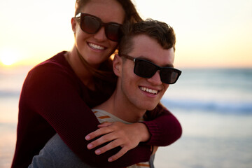 Happiness is a four letter word. Cropped portrait of an affectionate young man piggybacking his girlfriend at the beach.