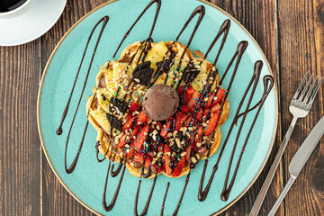 Heart waffle with pineapple and strawberry with gummy candy and ice cream on it.