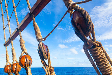 Part of an old sailing wooden ship with a rope ladder with pulleys, knotted ropes and wooden...