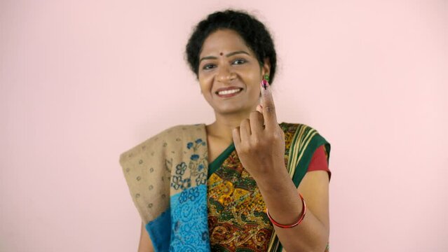 A beautiful lady shows her ink-marked index finger on her left hand after voting - state elections  a responsible citizen  an Indian citizenship. A middle-aged woman wearing a traditional Saree pos...