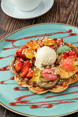 Heart waffle with banana and strawberry with gummy candy and ice cream on it.