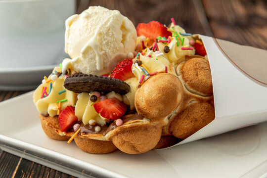 Hong kong or bubble waffle with ice cream, fruits, chocolate sauce and colorful candy