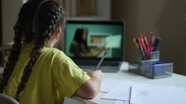 Online school, webcam lessons. Child distance education at home at table with laptop. Girl virtual education college. Technology of online video lessons. Video call of teacher to child. Virtual School
