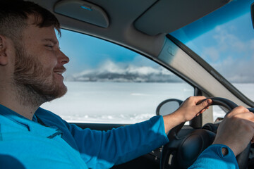 man hands on steering wheel winter road trip