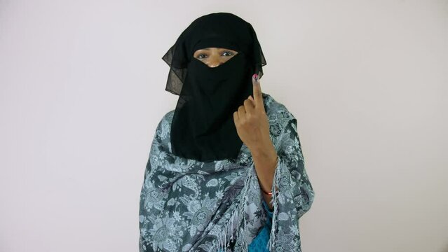 A Muslim woman in hijab showing her ink-marked finger after voting - an Indian citizen  state elections  a democratic country. A Muslim lady / female candidate wearing a black headscarf posing for ...