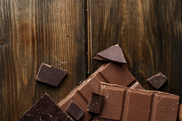 Broken chocolate bars on dark wooden background
