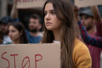 Crowd of young people protesting - focus on a young woman with a placard saying 