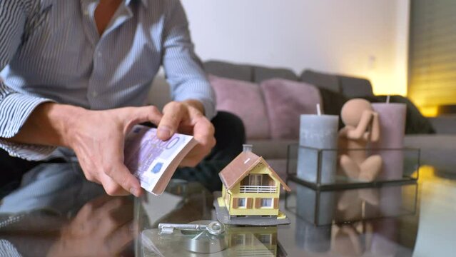 Male Businessman counting 500 euro banknotes and take key for house - Decision between cash money or property of villa - close up shot