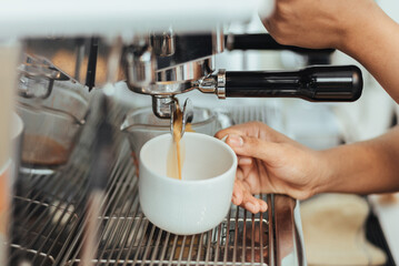Barista making coffee with coffee machine in coffee shop. Close up of hands barista to making espresso shot with machine. Coffee owner concept.
