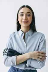 Vertical image of businesswoman in striped shirt keeping arms crossed, smiling at camera against...