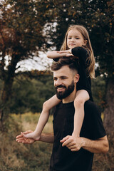portrait of father and child. A stylish father with a beard keeps on his arms a child, a little...