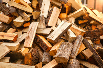 Background in the form of firewood chopped for heating the house, stacked randomly. Closeup.