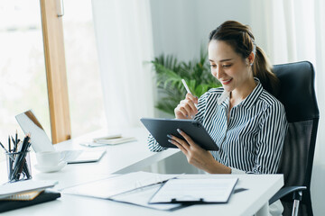 Beautiful attractive young asian business woman working with tablet at the office.