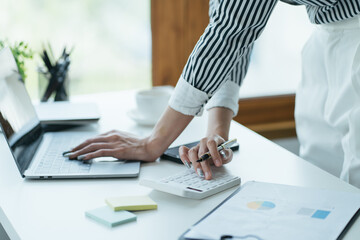 female accountant using calculator and typing on laptop. finance accounting plan concept