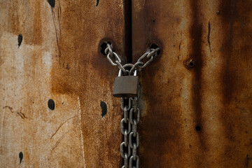 Padlock, the lock of the door of a rusty warehouse, a door bound with a chain and locked on it, close-up door lock