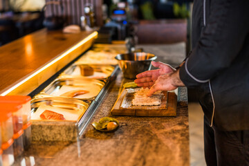 Sushi chef preparing Sushi at sushi restaurant.