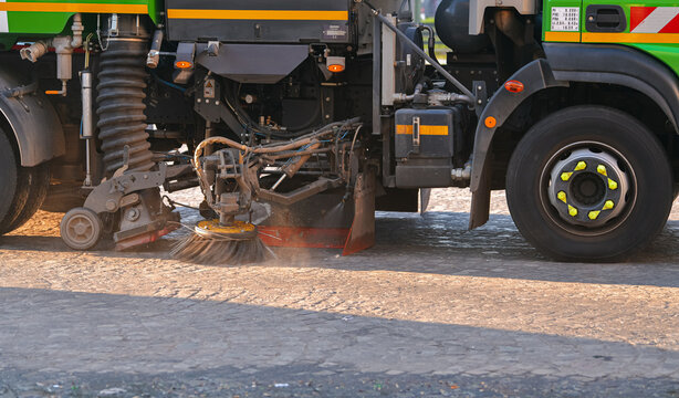 Public service truck cleaning the paved streets of dust and mud in morning light. Road infrastructure industry.