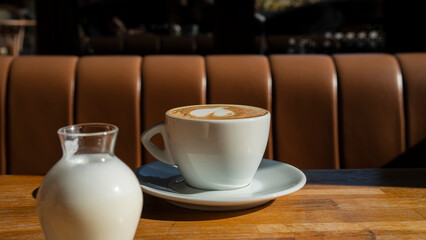 A cup of aromatic coffee on a wooden table in a cafe. Morning sun illuminates breakfast.