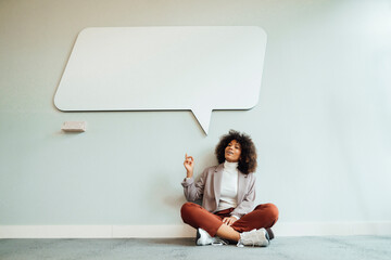 Businesswoman pointing at speech bubble board in office