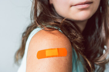 woman showing covid-19 vaccination band-aid on her arm, protection from the pandemic and...