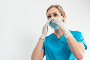 Caucasian millennial blonde dentist puts a protective mask on her mouth. High quality photo