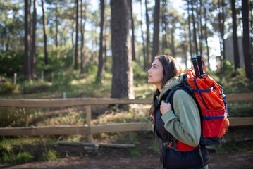 Side view of young female hiker. Caucasian woman in casual clothes with dark hair and big backpack. Hobby, nature concept