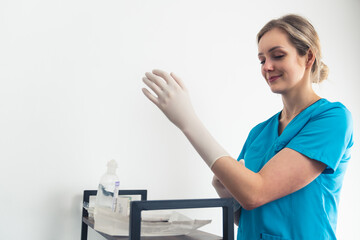 Young nurse in a blue uniform putting a latex glove on her hand. High quality photo
