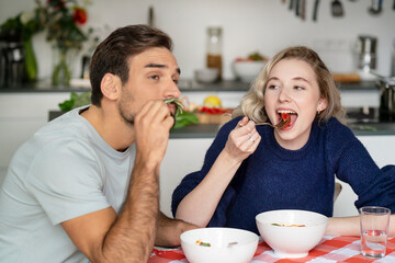 Young woman and man eating food sitting at table