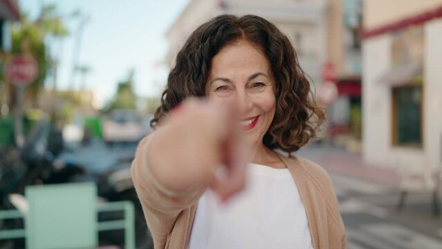 Middle age woman smiling confident doing come gesture with hand at street