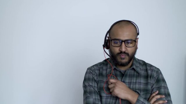 A close up shot of a remote Asian IT professional anxiously pacing around his office while talking into his headset, the man communicating with his colleague as they troubleshoot a technical issue