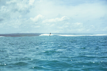 Obraz premium Surfing in Bali. A surfer in the ocean catches a wave.