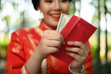 Asian pretty Chinese woman in cheongsam holding envelopen with banknote