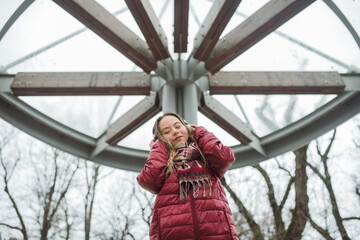 Fototapeta na wymiar Happy young woman with Down syndrome listening to music in town in winter