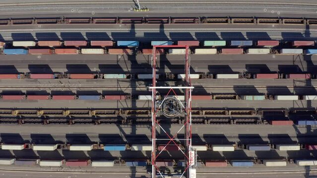 Flying above industrial railroad station with cargo trains and freight containers. Railroads and shipping container trains. Container train in the port. Cargo train moving in the container terminal. 