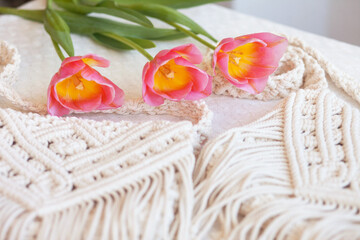 Handmade macrame bag with flowers on the light table. ECO friendly natural macrame cotton cross-body bag. Hobby knitting handmade macrame. Modern summer concept.