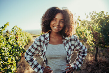 Beautiful mixed race farmer standing in vineyards with hands on hips - Powered by Adobe