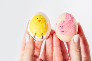 Easter eggs painted as rabbit and chicken in hand