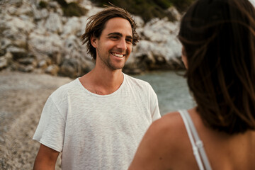 caucasian male smiling at girlfriend while walking along the beach
