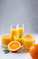 Fototapeta na wymiar Orange juice in glasses and fresh oranges on a gray background. Concept. Photo