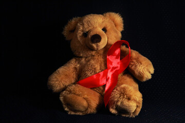 Toy bear on a black background with a red ribbon