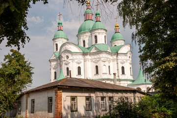 Christian orthodox white church with green domes with gold crosses. Calm blue sky above