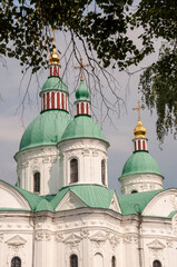 Obraz premium Christian orthodox white church with green domes with gold crosses. Calm blue sky above